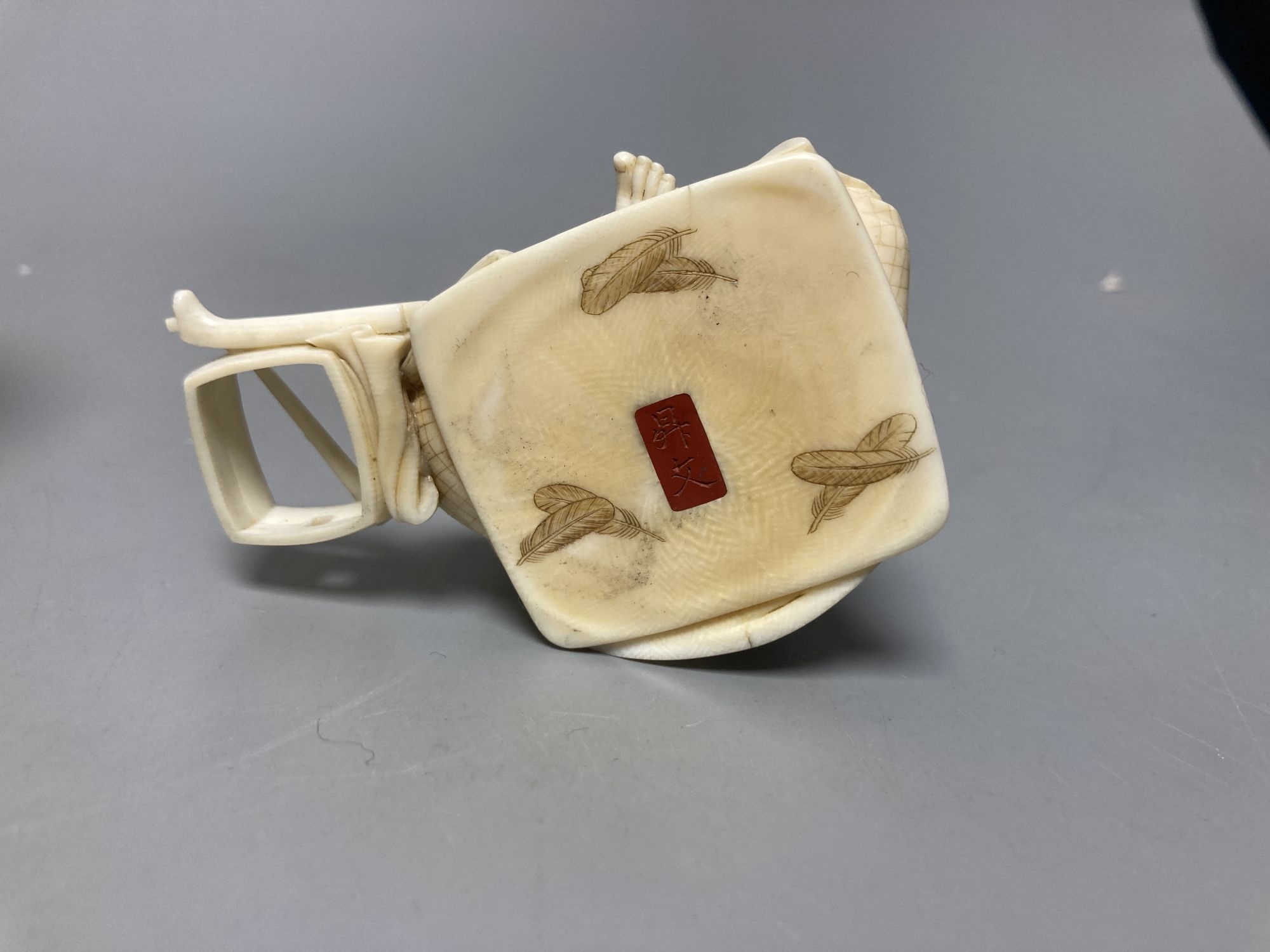 A Japanese ivory okimono of a furniture maker, signed tablet to base, Meiji period and a Chinese pierced ivory sleeve, height 6cm